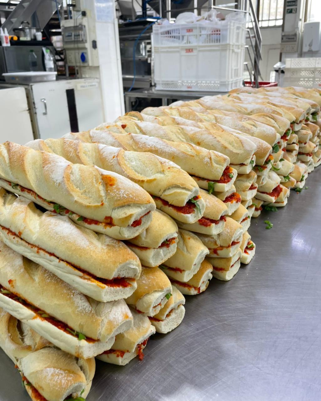Baguetes recheadas montadas e empilhadas na cozinha de produção.